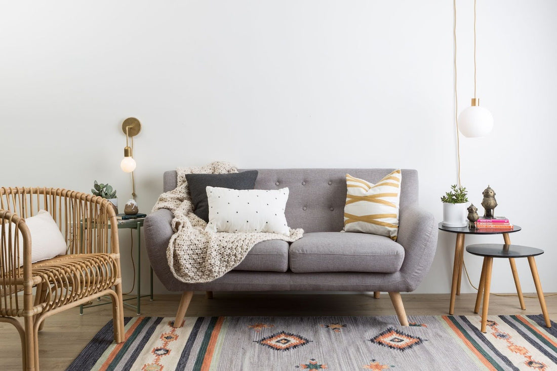 Neutral living room design with a grey couch, neutral light fixtures, wicker furnishing, and subtle earthy colors for accents