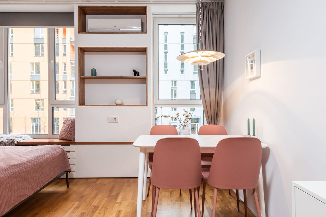 A one-bedroom apartment with a bed and small table lit by a customized hanging pendant light.