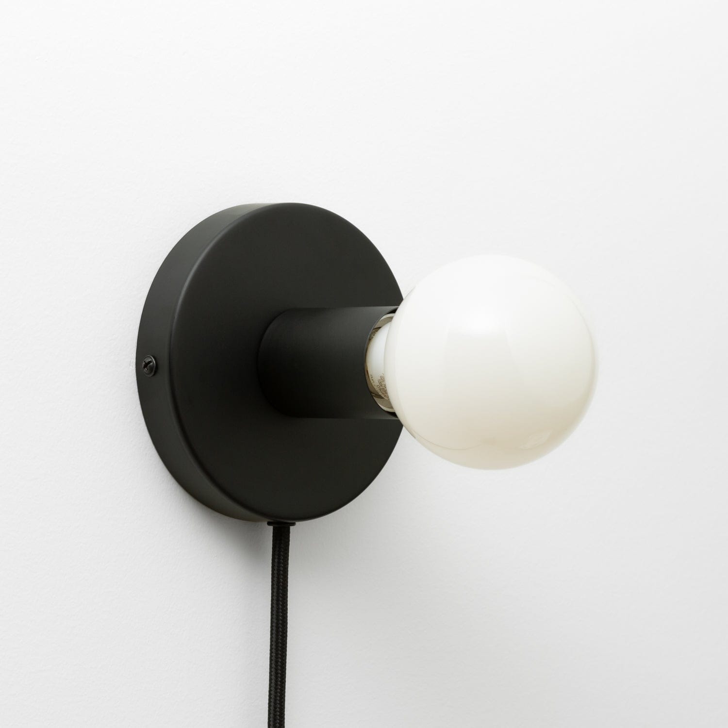 Button Plug-In Sconce in Matte Black finish with G25 light bulb