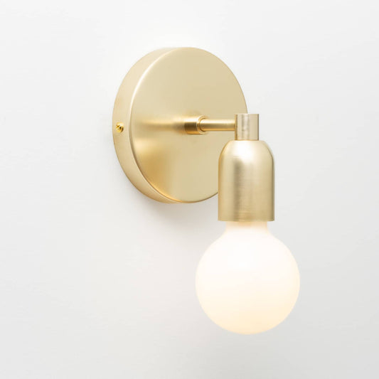 Junction Mini Solo Sconce in Raw Brass finish pictured with a G25 light bulb