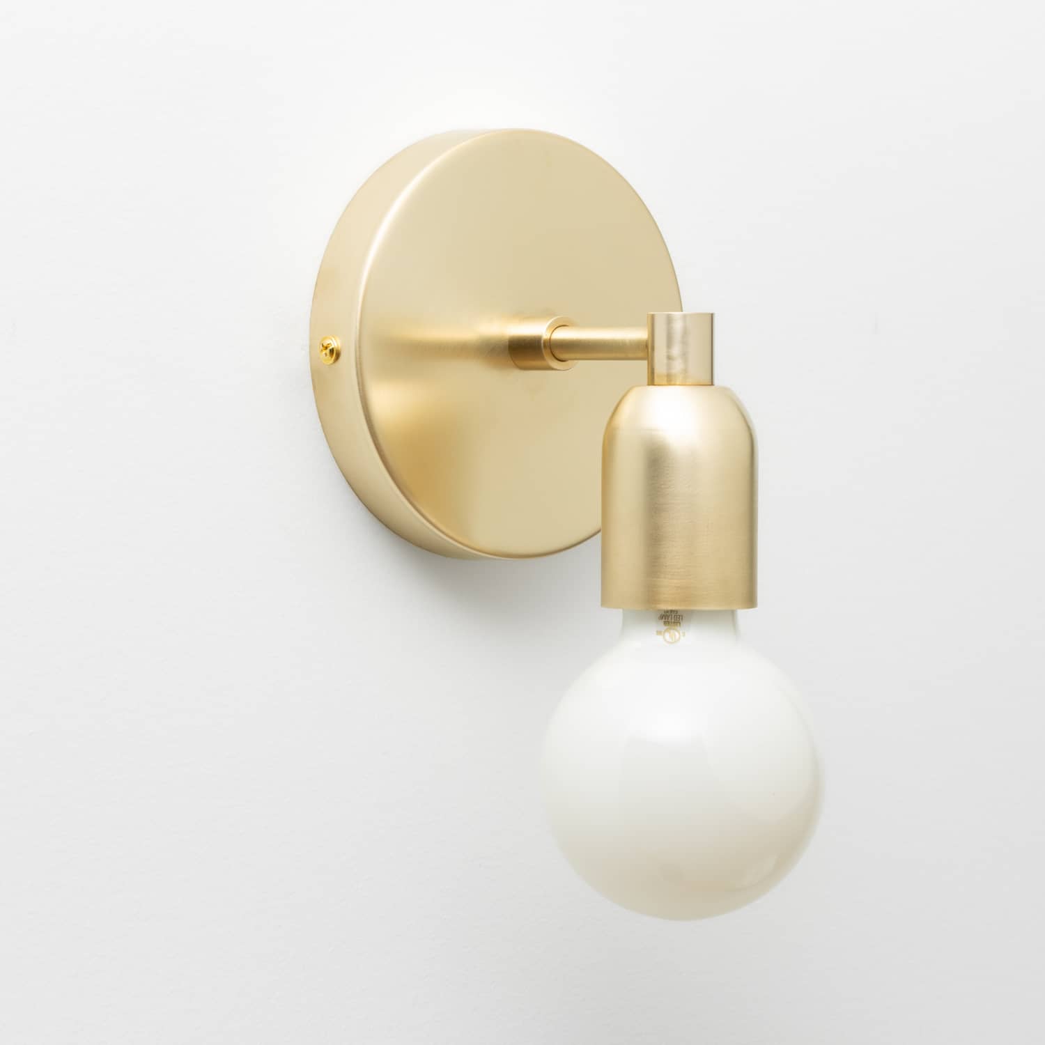 Junction Mini Solo Sconce in Raw Brass finish pictured with a G25 light bulb