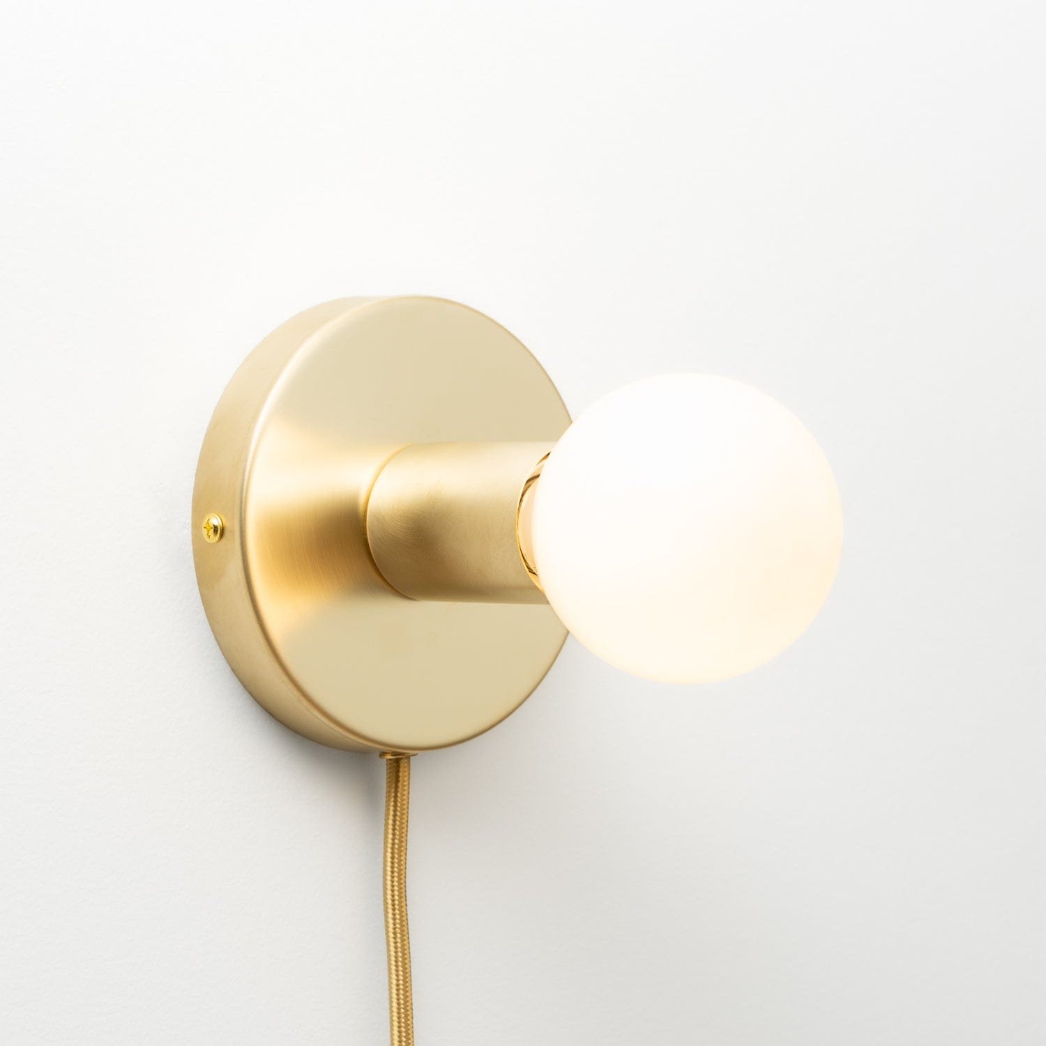 Button Plug-In Sconce in Raw Brass finish. Pictured with G25 light bulb.