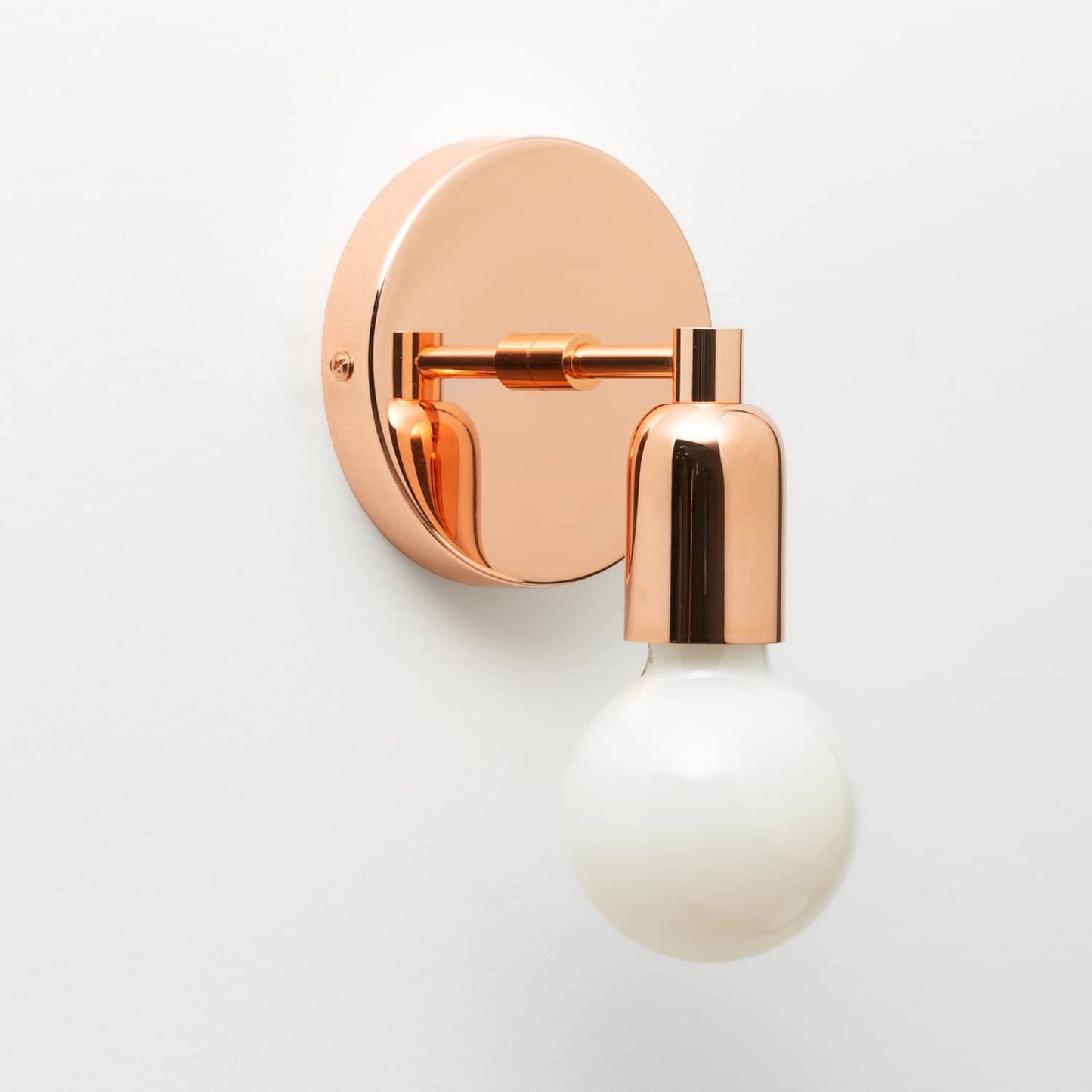 Junction Mini Solo Sconce in Polished Copper finish pictured with a G25 light bulb