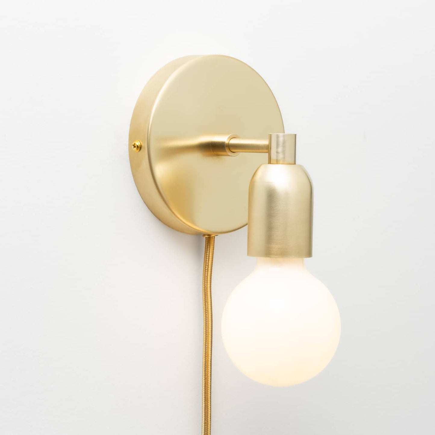 Junction Mini Solo Plug-In Sconce in Raw Brass finish pictured with G25 light bulb