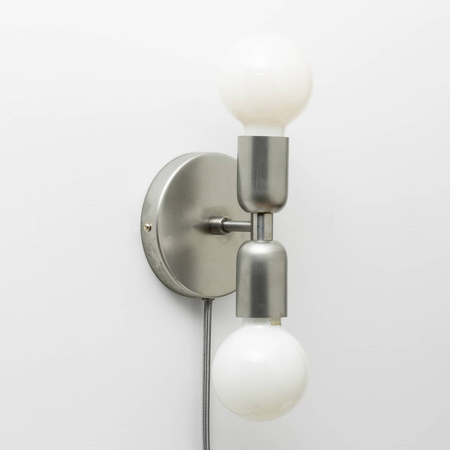 Junction Mini Duo Plug-In Sconce in Raw Metal finish with G25 milk glass light bulbs