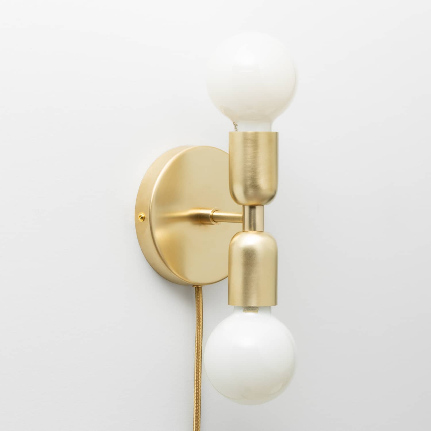Junction Mini Duo Plug-In Sconce in Raw Brass finish with G25 milk glass light bulbs