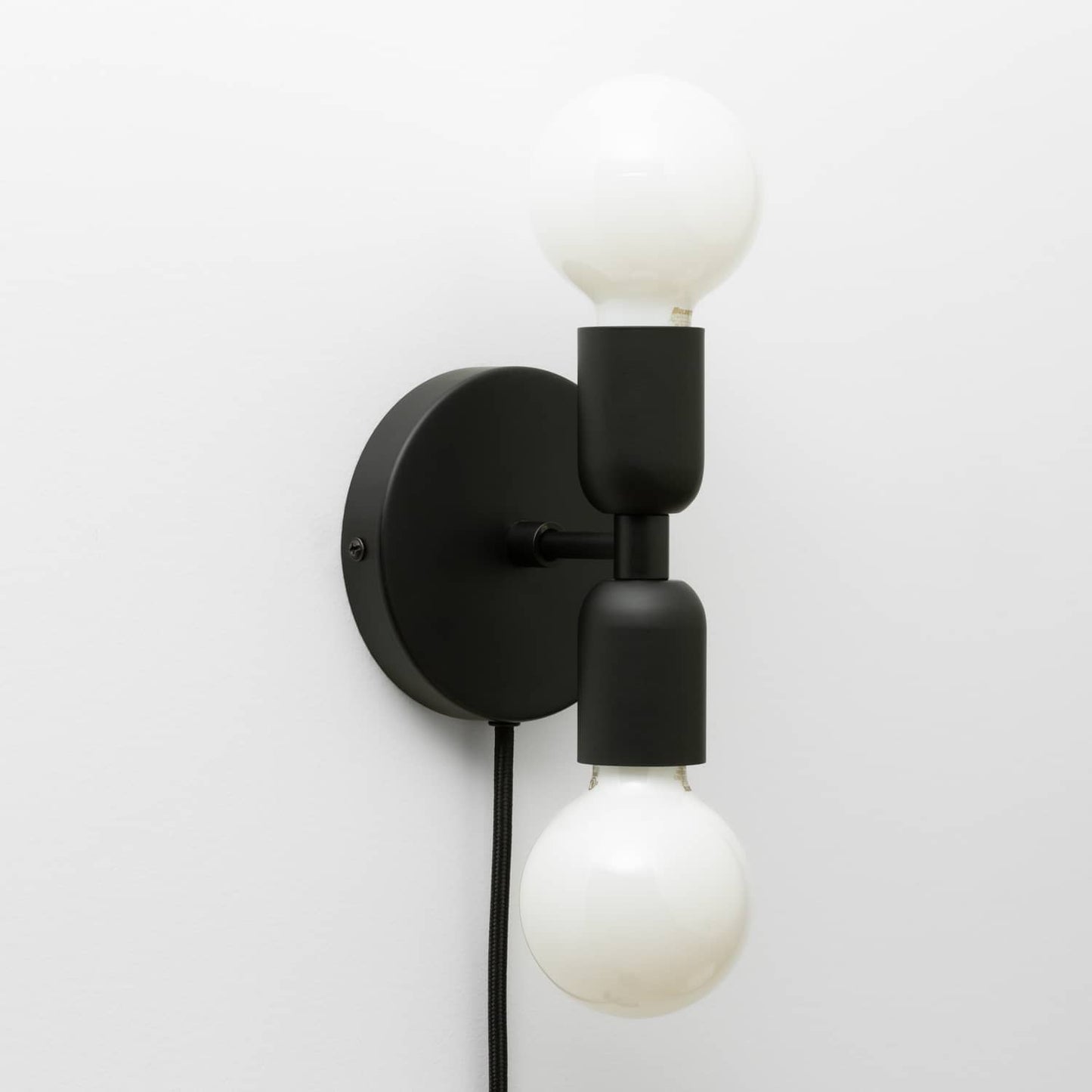 Junction Mini Duo Plug-In Sconce in Matte Black finish with G25 milk glass light bulbs