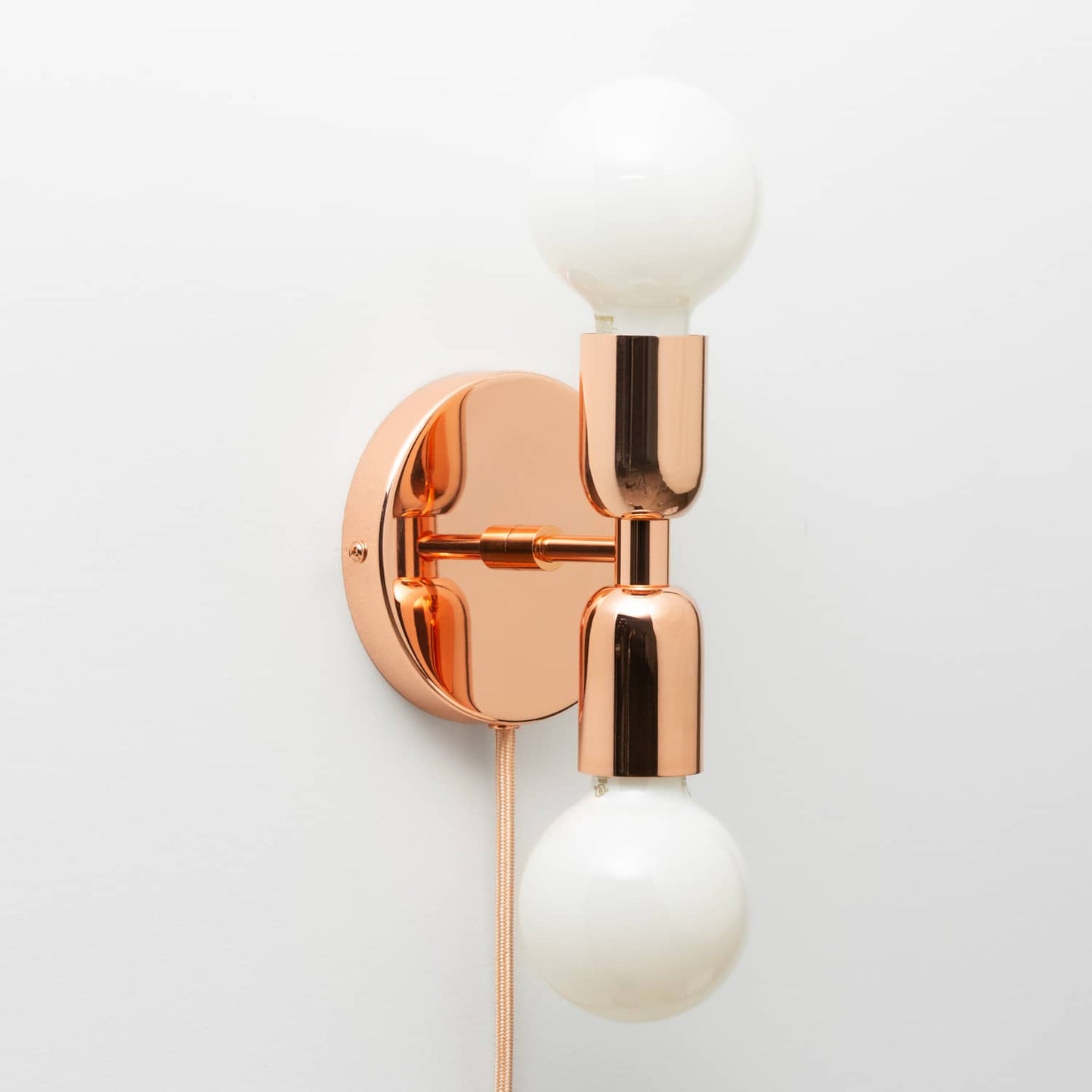 Junction Mini Duo Plug-In Sconce in Polished Copper finish with G25 milk glass light bulbs