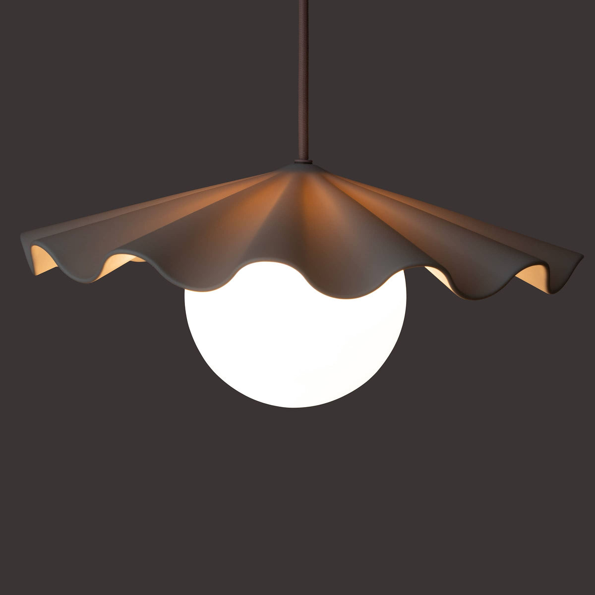 Fleur No. 3 porcelain pendant light glowing at night, raw porcelain shade with Quartz cord and hardware