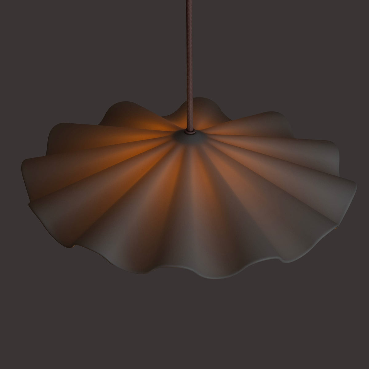 Fleur No. 3 porcelain pendant light glowing at night, raw porcelain shade with Quartz cord and hardware
