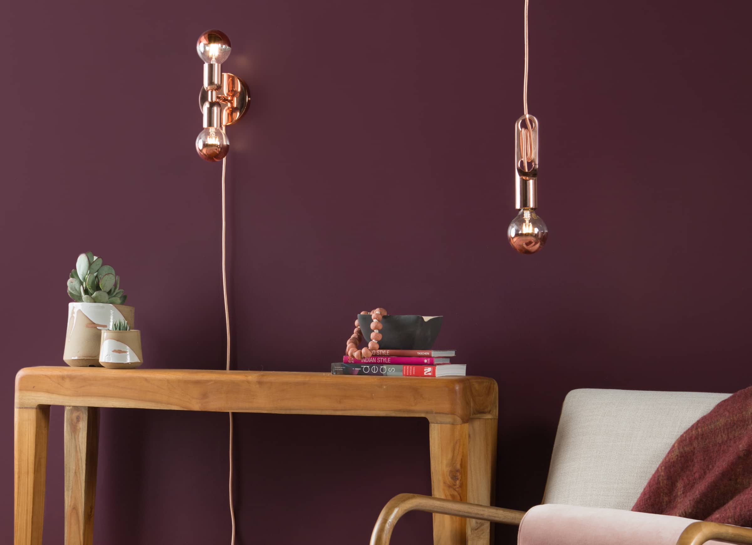 Room view with unction Mini Duo Plug-In Sconce in Polished copper on the wall above the console table. Wrap pendant in Polished copper above the chair