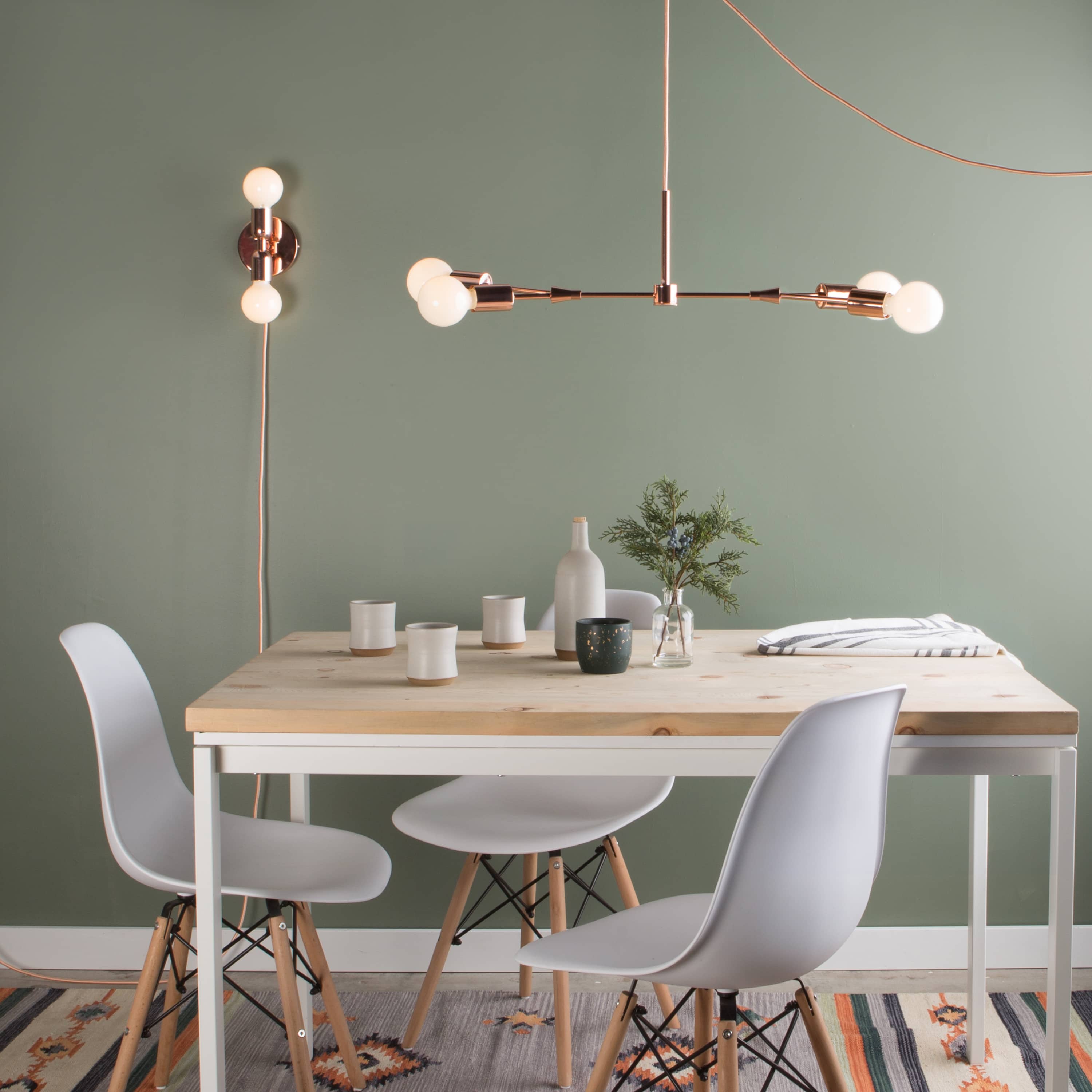 Dining room setting featuring Junction Mini Duo Plug-In Sconce on the wall and a Twig Chandelier above the table.